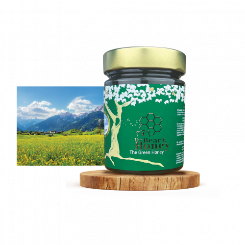 Ein Glas Griechischer Waldhonig "Grüner Honig" auf einem Holzbrett vor einem Bild einer Wiese