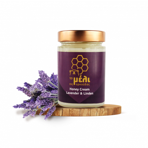 Ein Glas Honigcreme aus Lavendel und Lindenblüten auf einem Holzbrett neben einem Lavendelzweig